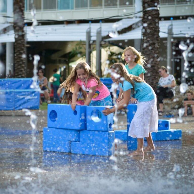 children playing with big blue blocks outside in water