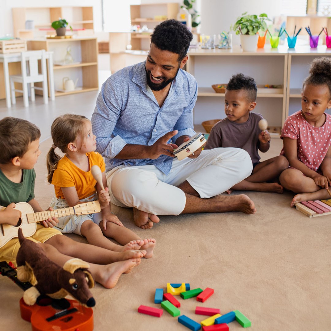 adult and children playing with musical instruments in classroom