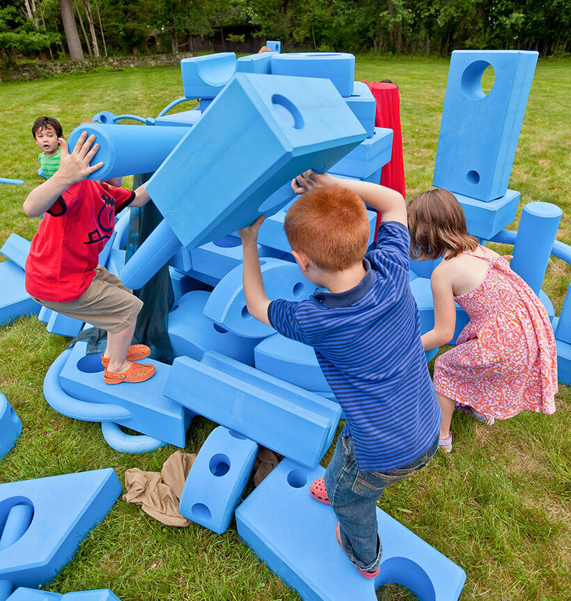 a group of kids playing with big blue blocks
