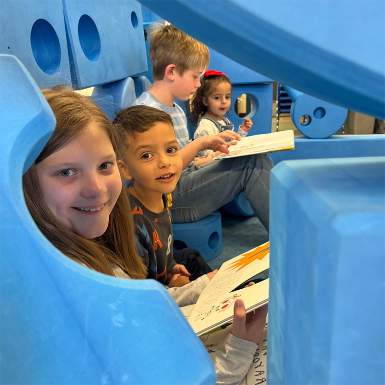 children reading books and playing with big blue blocks