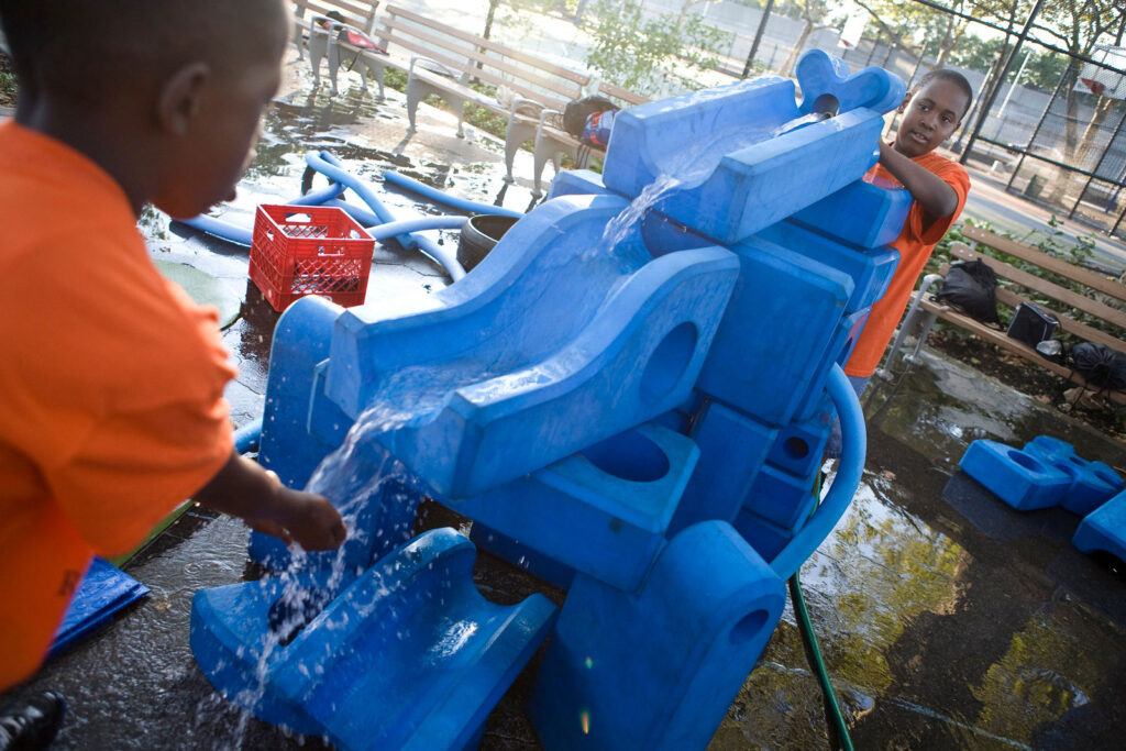 kids playing with water and big blue blocks outside